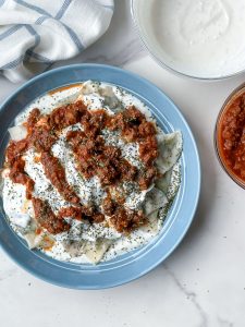 Ashak, a beloved Afghan dish of delicate dumplings filled with leeks and herbs. Served with hearty tomato sauce, creamy garlicky yogurt, and a sprinkle of aromatic dried mint. Savor the goodness of Ashak!