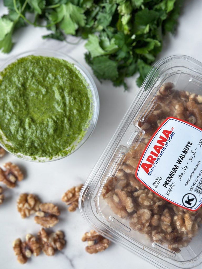 a box of premium walnuts from Ariana Sweets Inc next to a bowl of cilantro green chutney