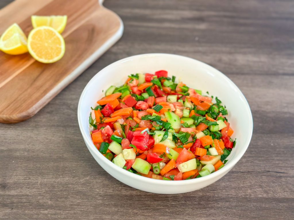 a bowl of salata. cucumbers. carrots. green onions. tomatoes and cilantro