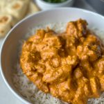 a bowl of butter chicken made by halfghan kitchen with a bed of rice