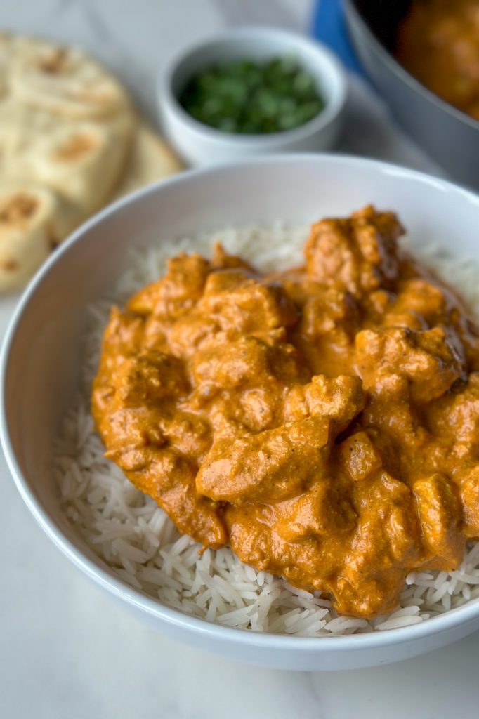 a bowl of butter chicken made by halfghan kitchen with a bed of rice