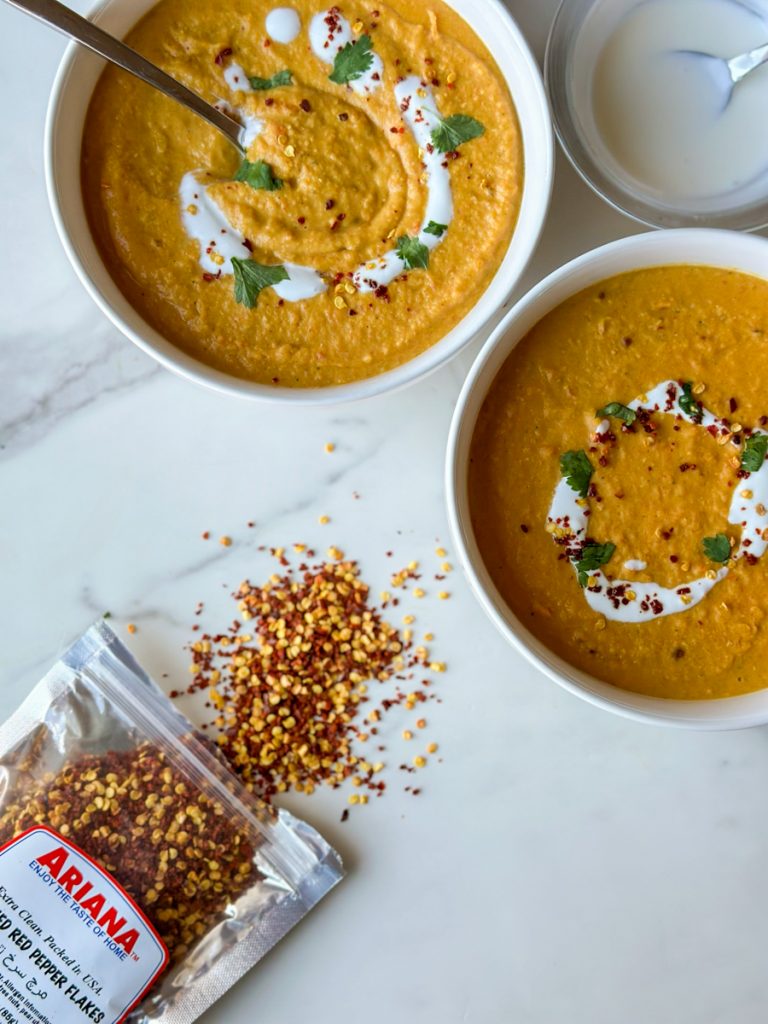 To make this creamy red lentil soup, begin by sautéing onions and minced garlic in oil. Then add carrots and seasonings. Cook for a few minutes, then add tomato paste, red lentils, and water. Bring to a boil, then cover and cook on super low for 30 minutes, or until lentils and carrots are soft. Blend until smooth, then add heavy cream. Add more heavy cream if a more soupy consistency is desired. Top with red pepper flakes and cilantro and enjoy!